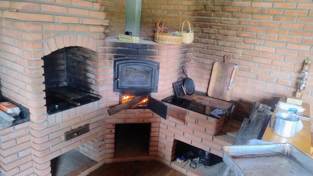 a brick oven with a stove in a kitchen at Recanto pôr do sol in Camanducaia