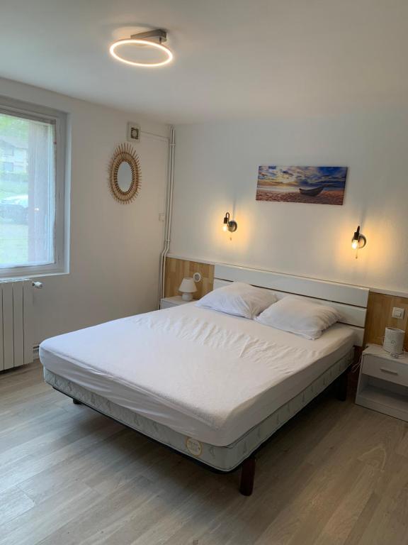 une chambre avec un grand lit avec des draps blancs dans l'établissement Résidence la Jonquière, à Cazaubon