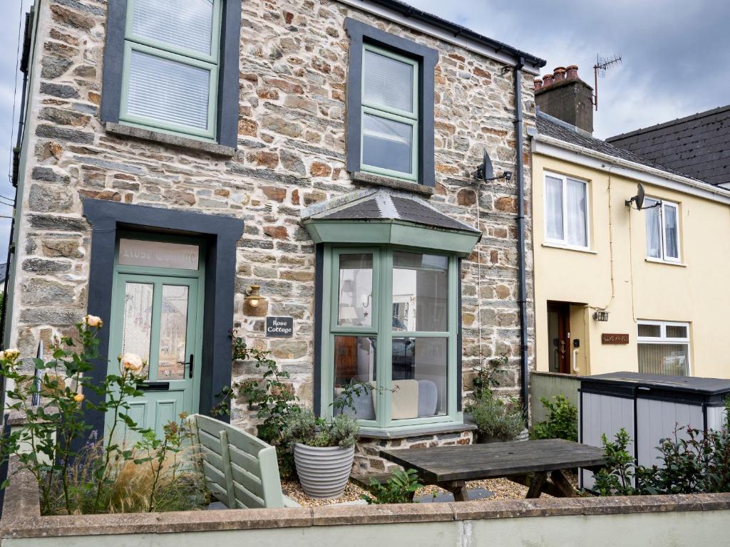 ein Backsteinhaus mit einem Tisch davor in der Unterkunft Rose Cottage in Cardigan