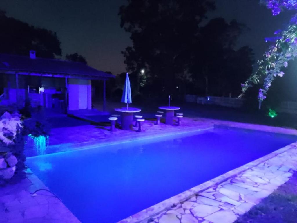 a swimming pool at night with a table and umbrella at Sítio jardim in São Pedro da Aldeia