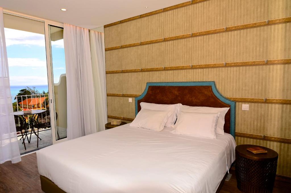 1 dormitorio con cama blanca y balcón en Vila Toca, en Funchal