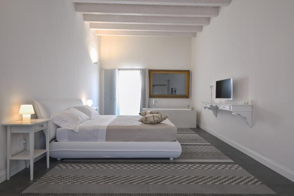 ein weißes Schlafzimmer mit einem Bett und einem TV in der Unterkunft Tenuta il Bosco in Bitonto