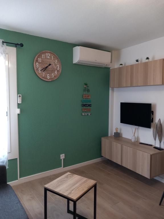 a living room with a clock on a green wall at Studio climatisé avec une place de parking et classé 2 étoiles à la Faviére in Bormes-les-Mimosas