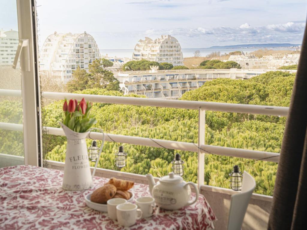 une table avec une assiette de nourriture et une vue sur les bâtiments dans l'établissement Apartment Les Jardins du Couchant-7 by Interhome, à La Grande Motte
