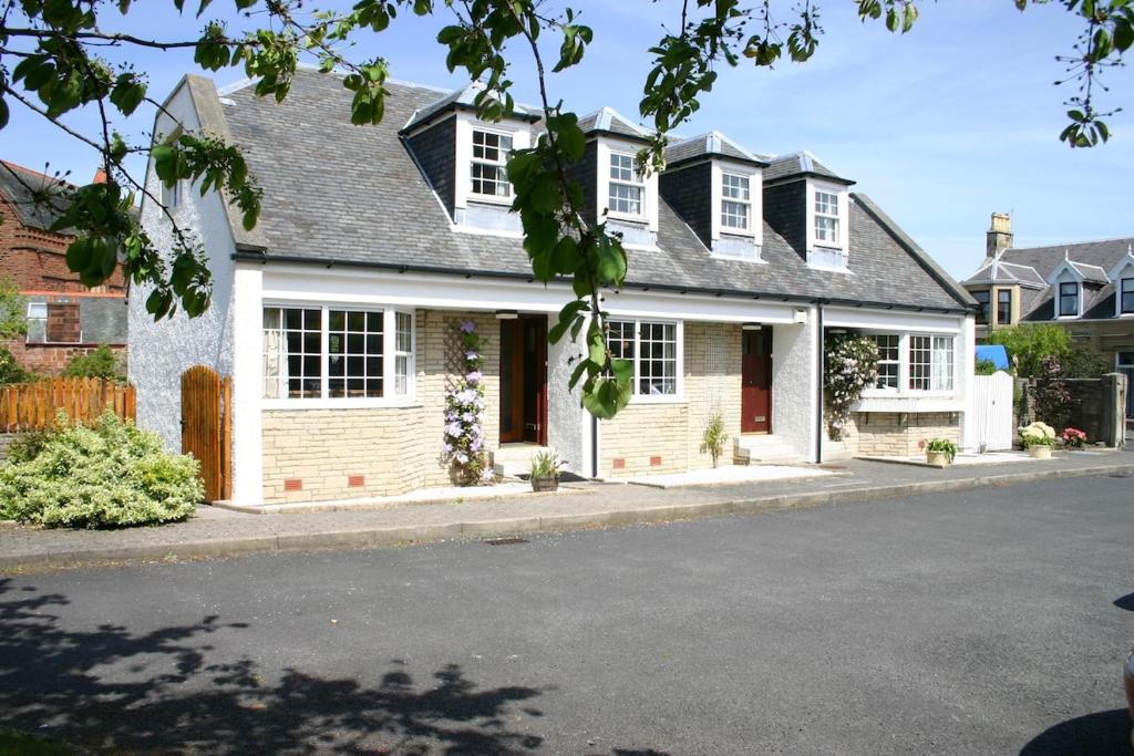 a white house with white windows on a street at Church Cottage with sunny garden in Ayr