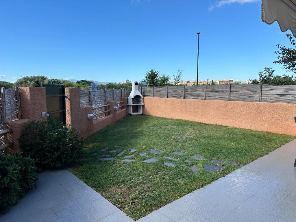 a backyard with a lawn with a fence and a small garden at Beautiful Apartment with Swimming Pool in Olbia