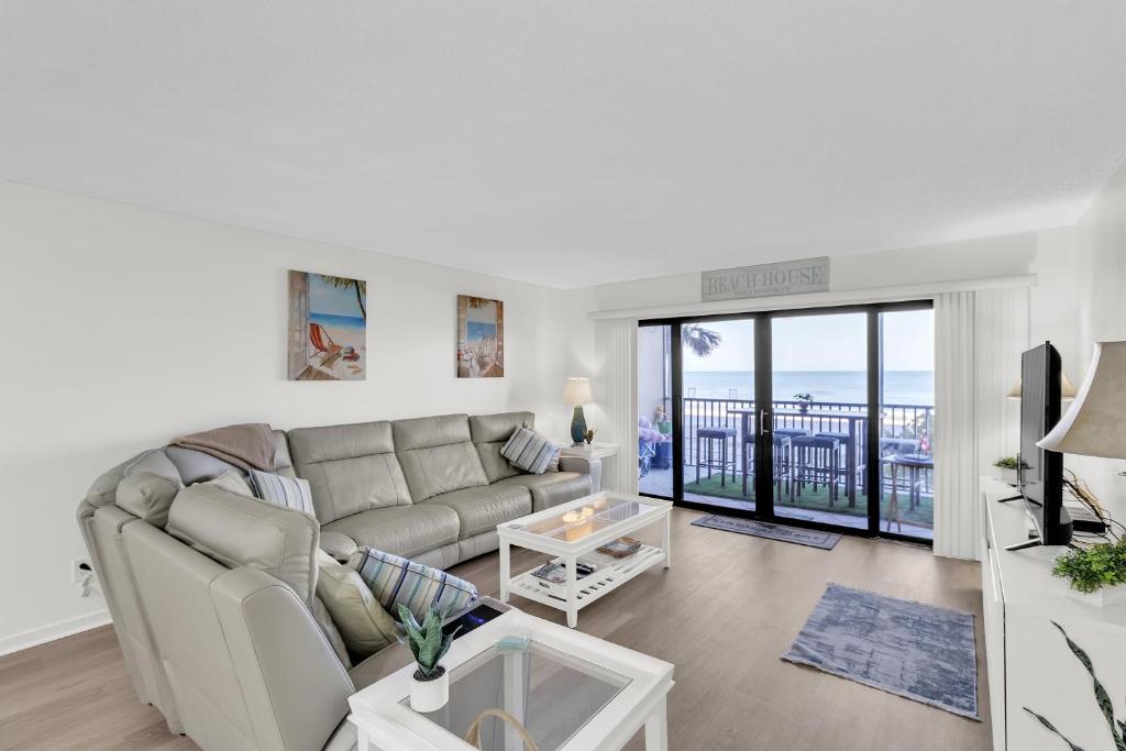 a living room with a couch and a balcony at Magnificent Gulf Front Condo Located Directly on the Ocean! condo in Indian Rocks Beach
