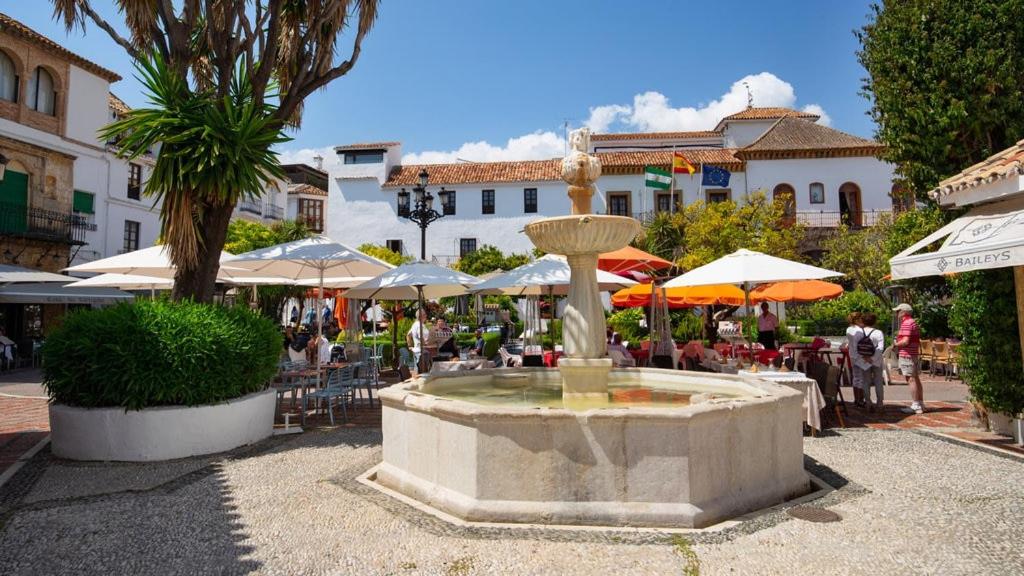 a fountain in a courtyard with people sitting at tables at Apartamento Plaza de los naranjos in Marbella