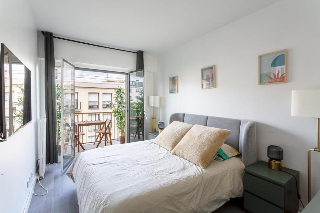 une chambre avec un grand lit et un balcon dans l'établissement Appartement Neuilly, à Neuilly-sur-Seine