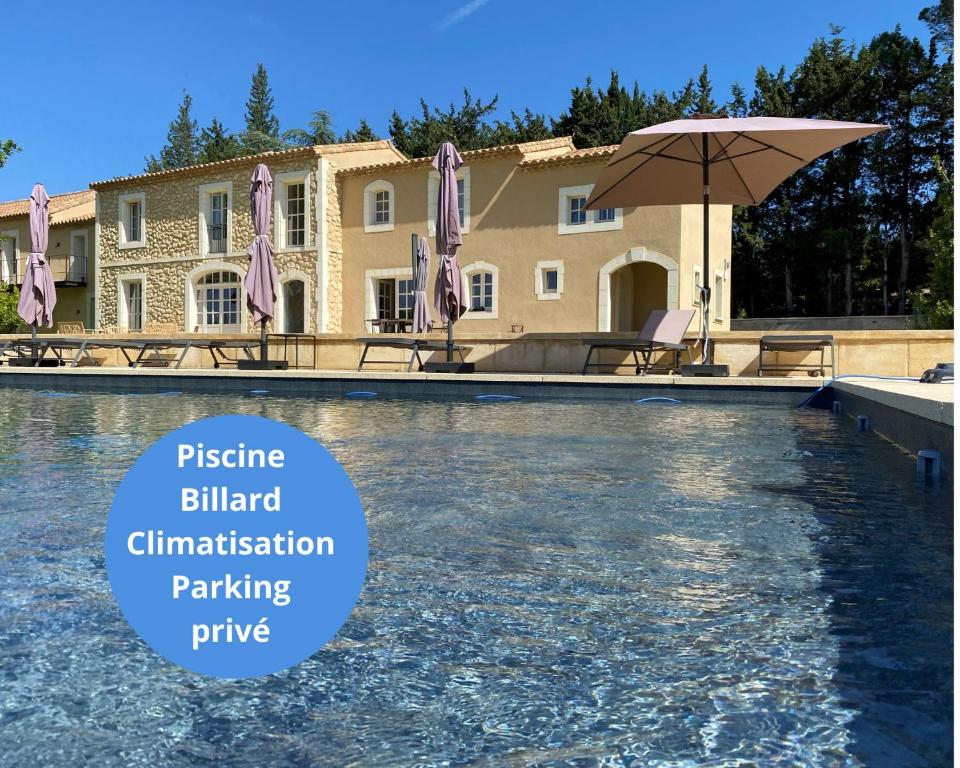 - une piscine avec un parasol en face d'une maison dans l'établissement Superbe Mas Provençal rénové avec piscine, billard et climatisation à Paradou, à Paradou