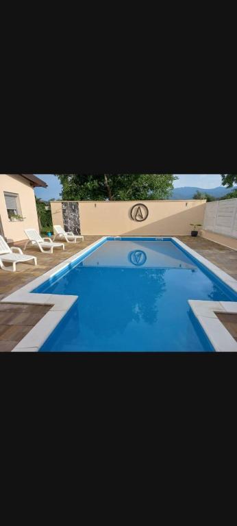 a large blue swimming pool with white chairs around it at Villa Aida in Bihać