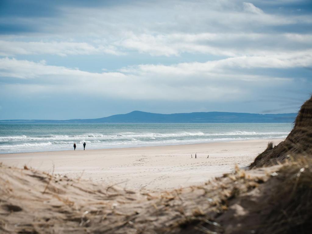 two people walking on a beach near the ocean at Apartment Harbour Nights 7F by Interhome in Lossiemouth