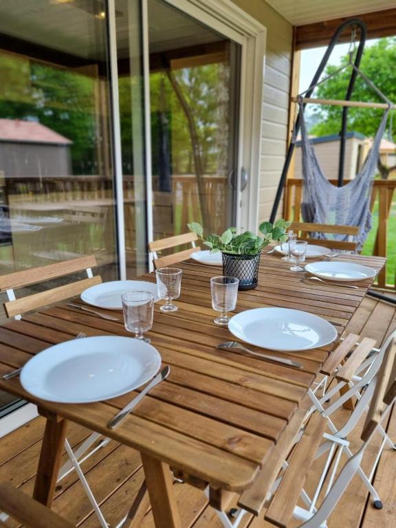 - une table en bois avec des assiettes et des chaises sur une terrasse couverte dans l'établissement Sous la canopée - le calme au bord du lac, à Labouheyre