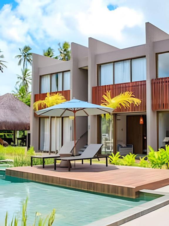 a villa with a swimming pool and a table with an umbrella at Flat with Direct Pool Access in Japaratinga