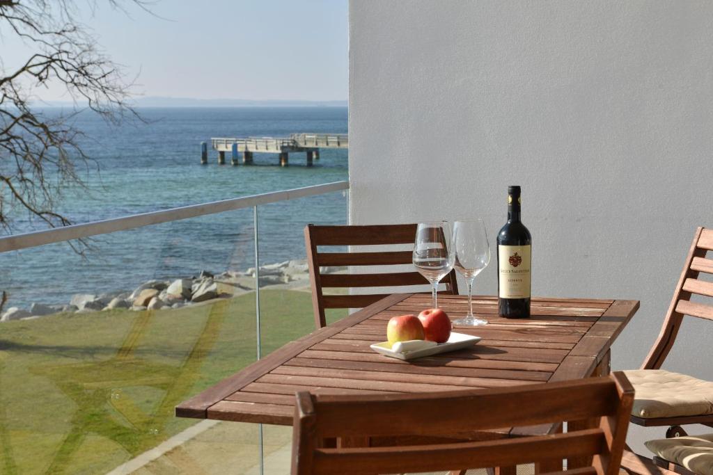 a wooden table with a bottle of wine and two glasses at Penthouse Ostseeresidenz in Sassnitz