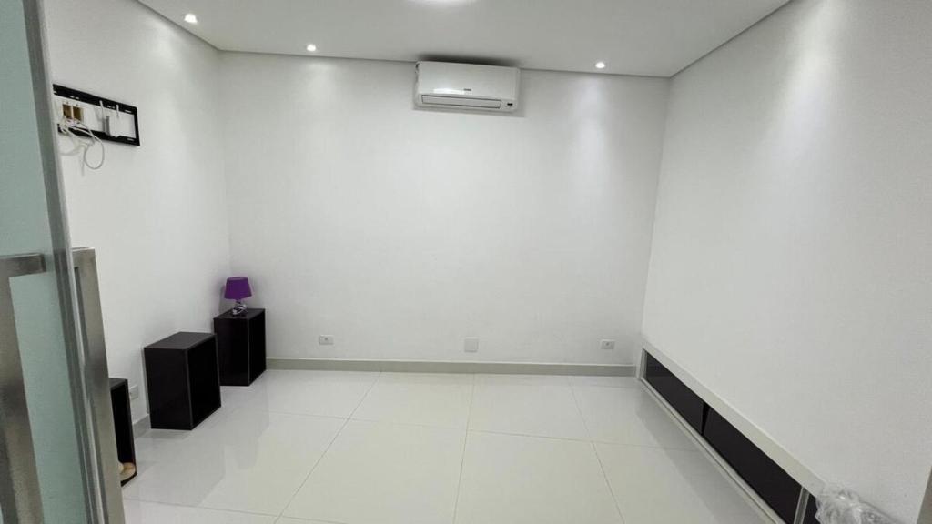 an empty room with a white wall and a fan at Apto Guaruja in Guarujá