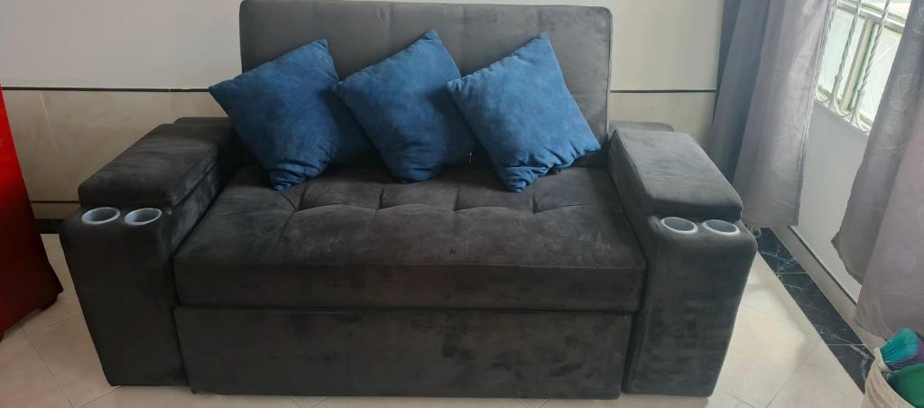 a brown couch with three blue pillows on it at Increíble apartamento norte Tunja in Tunja
