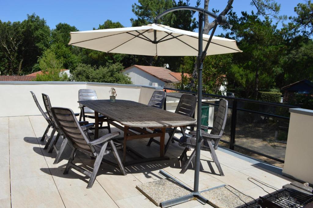 une table et des chaises avec un parasol sur une terrasse dans l'établissement Maison Familiale Chaleureuse à Deux Pas de la Plage, à Saint-Brévin-lʼOcéan