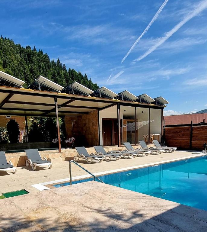 a group of lounge chairs sitting next to a pool at Pensiunea El Monte SPA in Rucăr