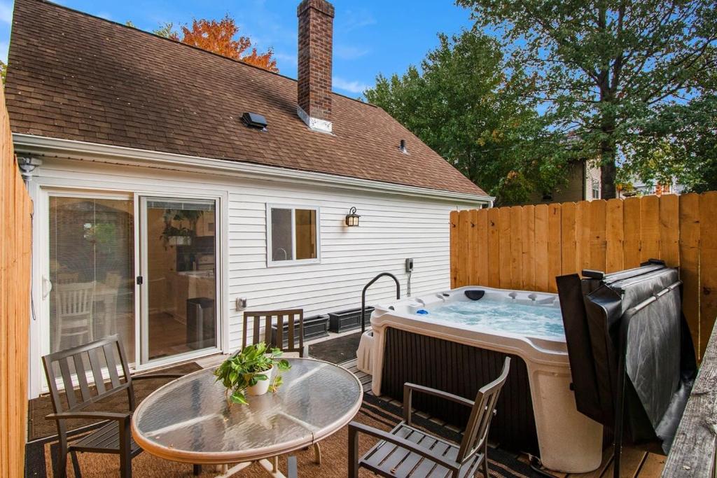 a backyard with a hot tub and a table and chairs at Beautiful Benson Cottage with Year-Round Hot Tub in Omaha