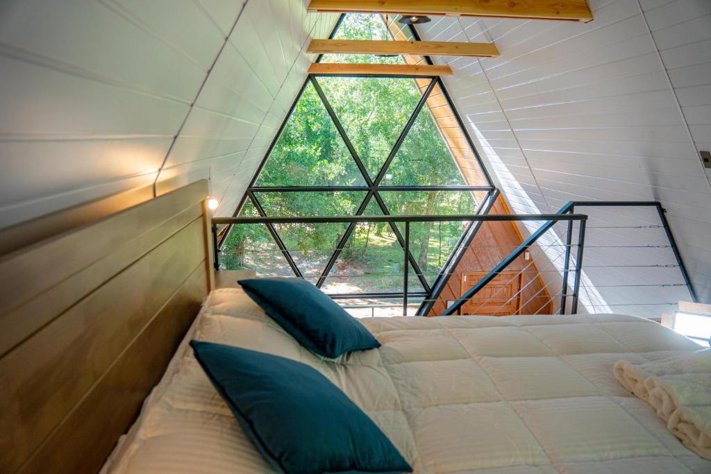 a bed in a room with a large window at Enarbol Lodge, Hot Tube en terraza in Pucón