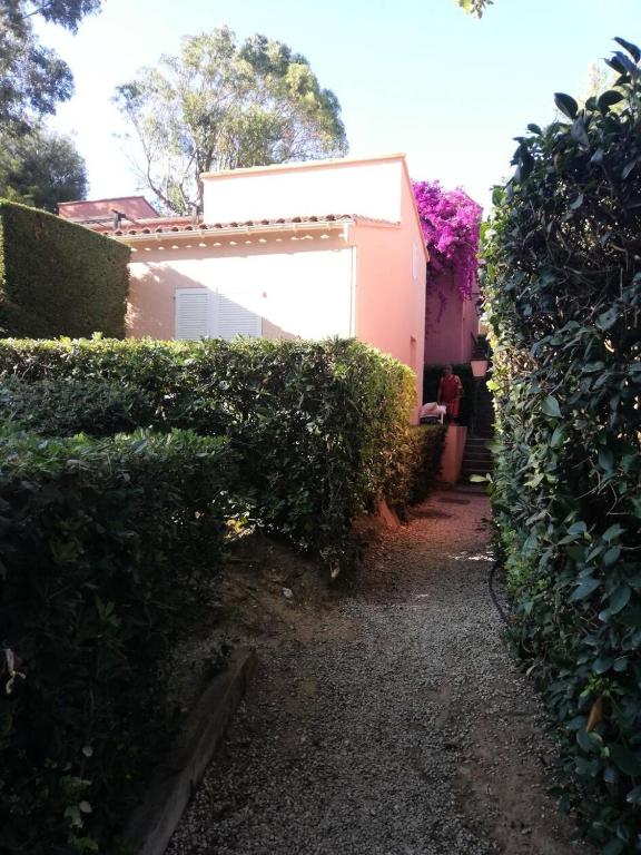 une haie devant une maison avec un bâtiment dans l'établissement Résidence Rouveau - Jolie petite maison au calme avec vue sur le jardin du domaine de la Coudoulière MAE-8691, à Six-Fours-les-Plages