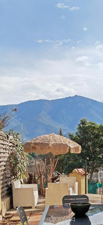 une terrasse avec des chaises et un grand parasol en paille dans l'établissement F2 cosy idéal pour les vacances, à Sarrola-Carcopino