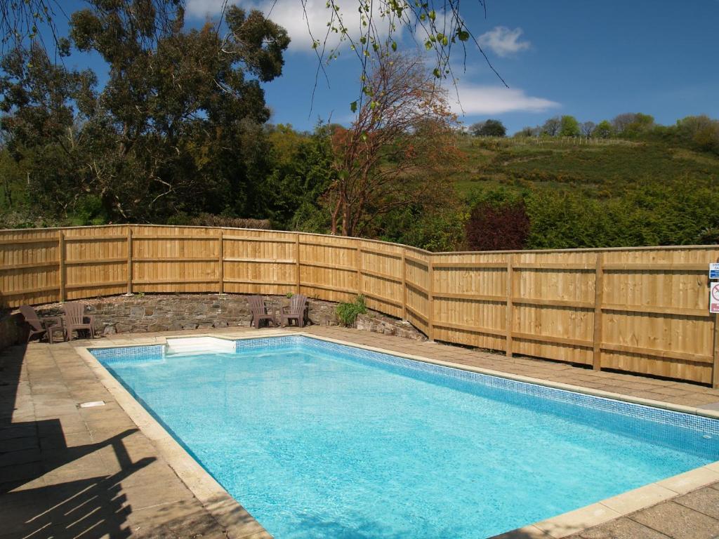 a swimming pool with a wooden fence next to it at Farm Stay with animal experiences, 30 minutes to Exmoor & Beaches, Pet friendly, Outdoor heated pool, Games barn, fast WiFi and parking in Barnstaple