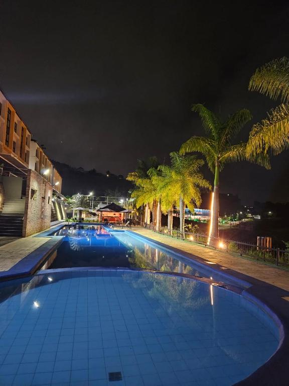 a large swimming pool with palm trees at night at Alto da Serra Villas - Flat 301 in Bananeiras