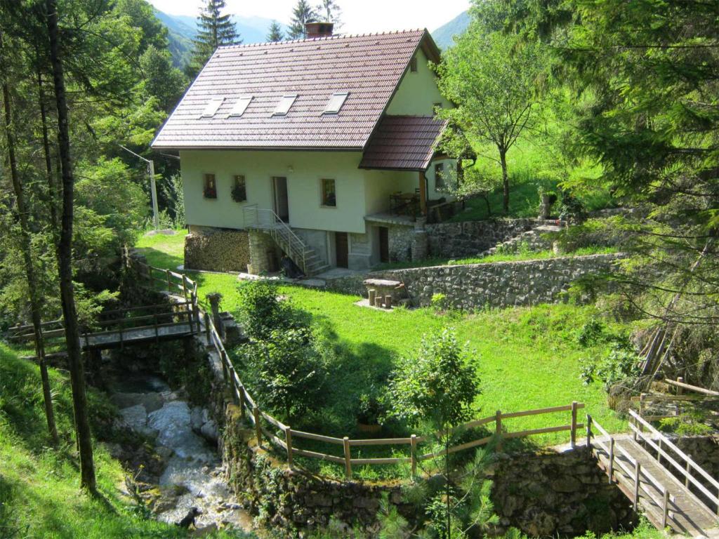une maison sur une colline avec un ruisseau devant elle dans l'établissement House Dolenja Trebuša, à Dolenja Trebuša