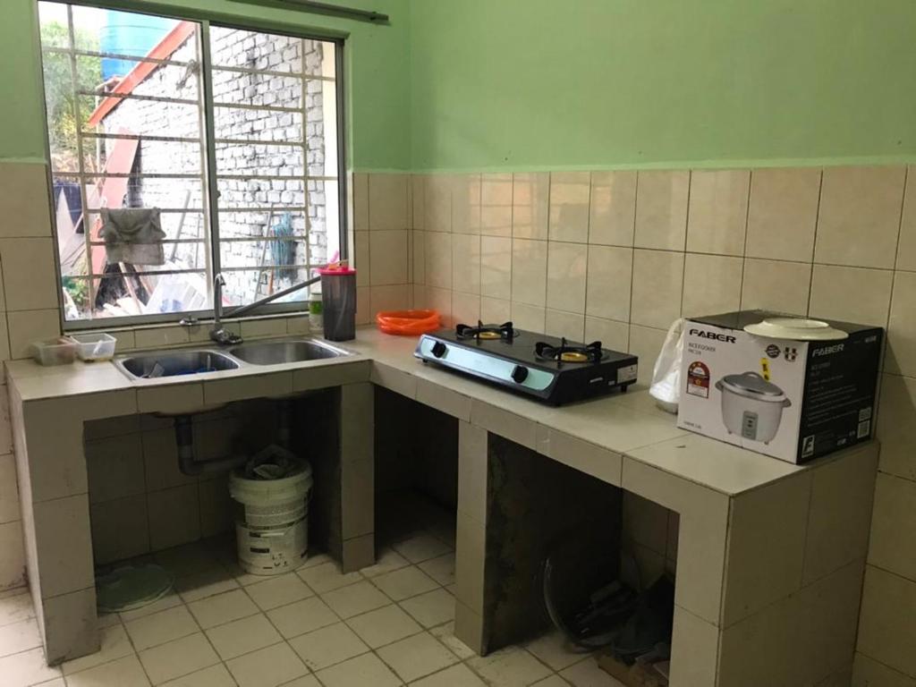 a kitchen with a counter with a microwave and a sink at Comfy Transit in Tawau