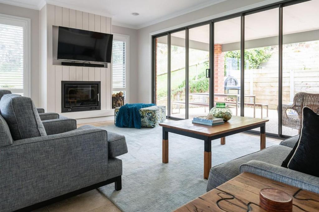a living room with two couches and a fireplace at Bundjil Beach House Inverloch in Inverloch