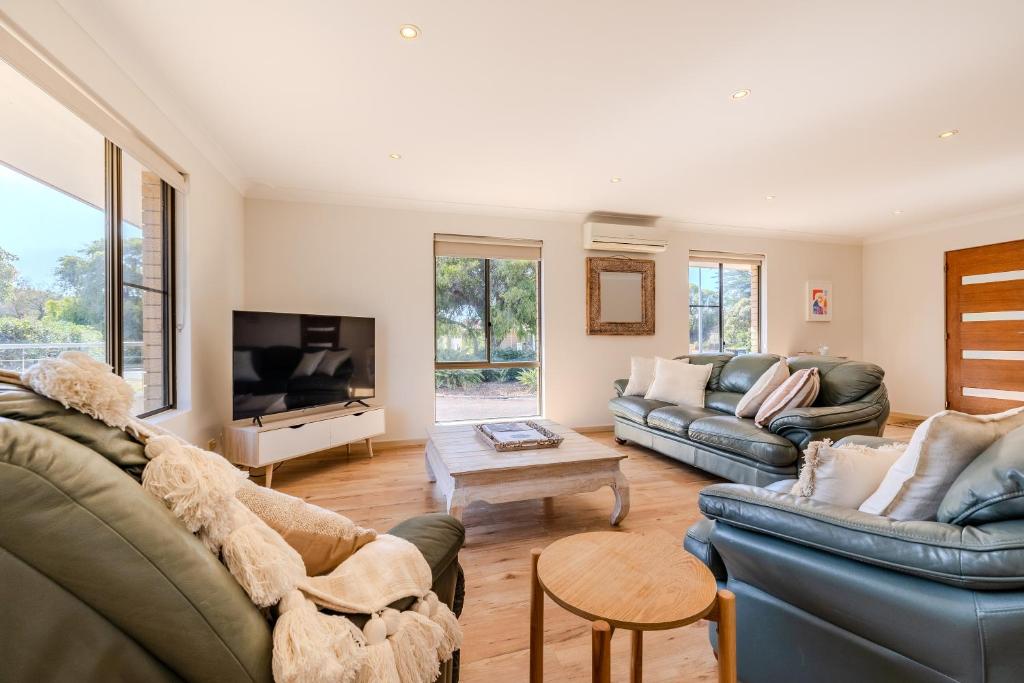 a living room with two couches and a tv at Morning Light Beach House - by the BnB Collection in Albany