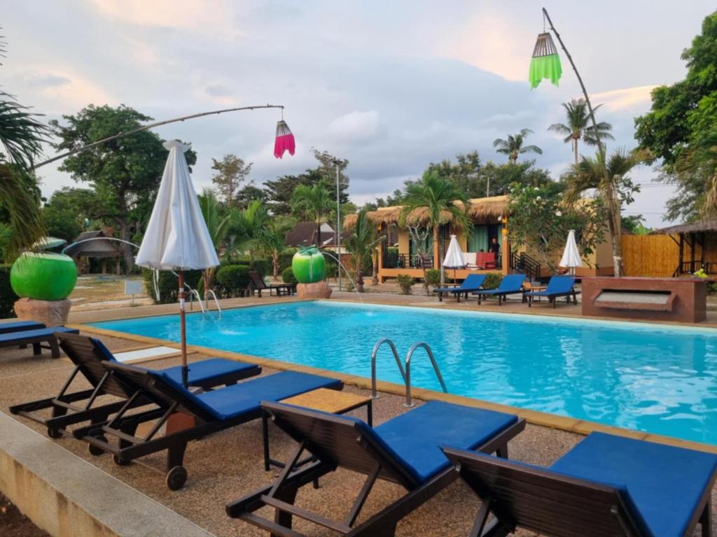 a pool at a resort with chairs and umbrellas at Sunny House Garden in Phra Ae beach