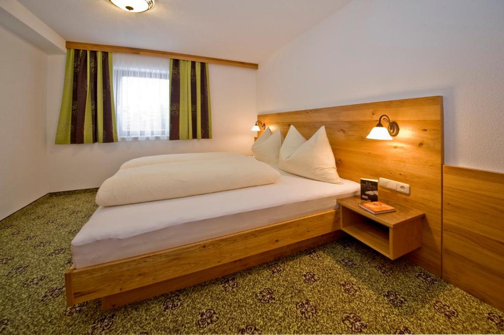 Schlafzimmer mit einem großen Bett mit einem Kopfteil aus Holz in der Unterkunft Apart Sonnenplateau in Serfaus