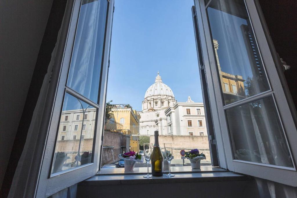 a window with a bottle of wine and a building at Stazione Vaticana 5 Apartment in Rome