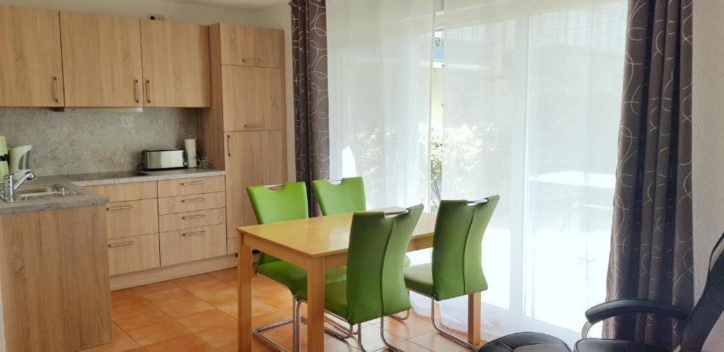 a kitchen with a wooden table and green chairs at Ostseeglück App9 in Zingst