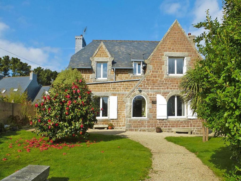 une maison en briques avec une brousse fleurie devant elle dans l'établissement Stone House Pleumeur-Bodou near Pink Beaches, à Pleumeur-Bodou