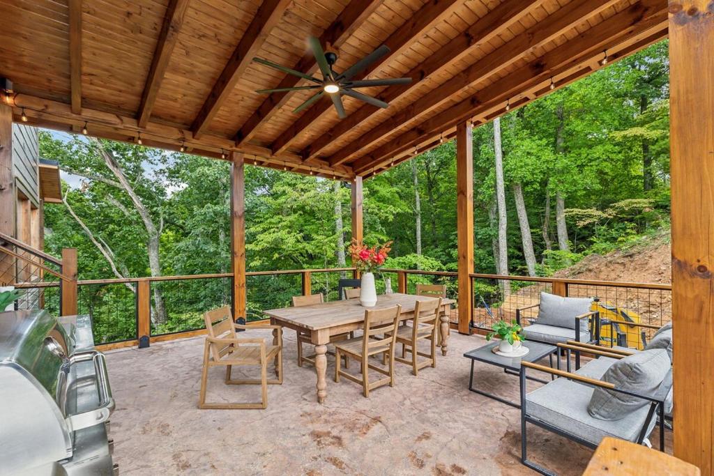 a patio with a table and chairs and a ceiling fan at Honeybear Hideaways - #1 Luxury Haven Cabin with Breathtaking Mountain Views, Indoor Pool, Bowling Alley, and Golf in Pigeon Forge