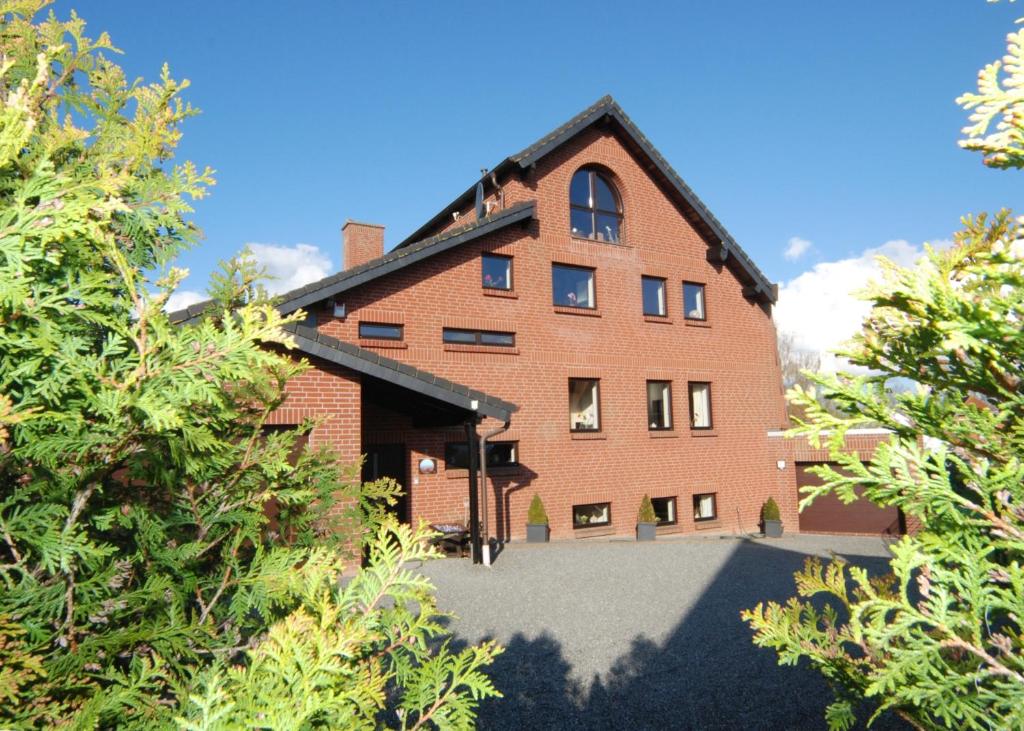 a red brick building with trees in front of it at Ferienwohnung Muschel in Heiligenhafen