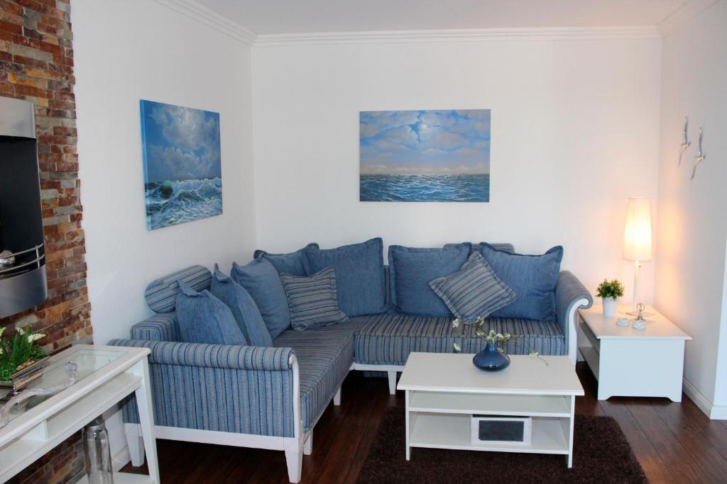 ein Wohnzimmer mit einer blauen Couch und einem Tisch in der Unterkunft LANDHAUS AM HAFEN im OG in Heiligenhafen