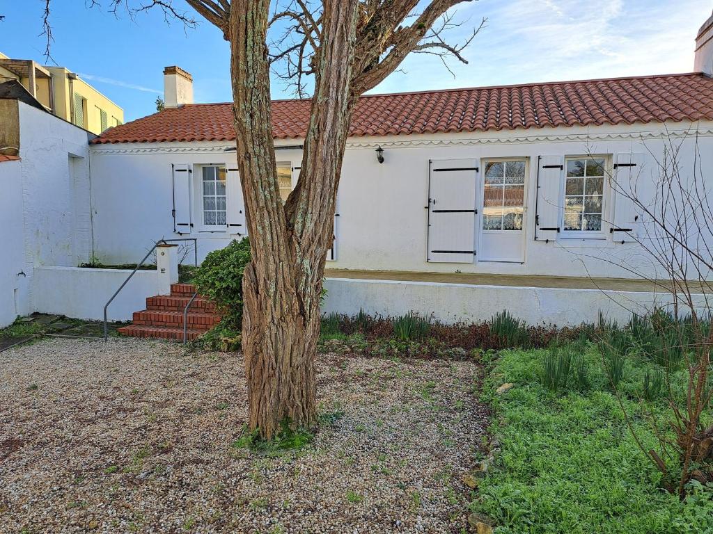 une maison blanche avec un arbre devant dans l'établissement Maison confortable en centre-ville avec jardin, Saint-Jean-de-Monts - FR-1-323-563, à Saint-Jean-de-Monts