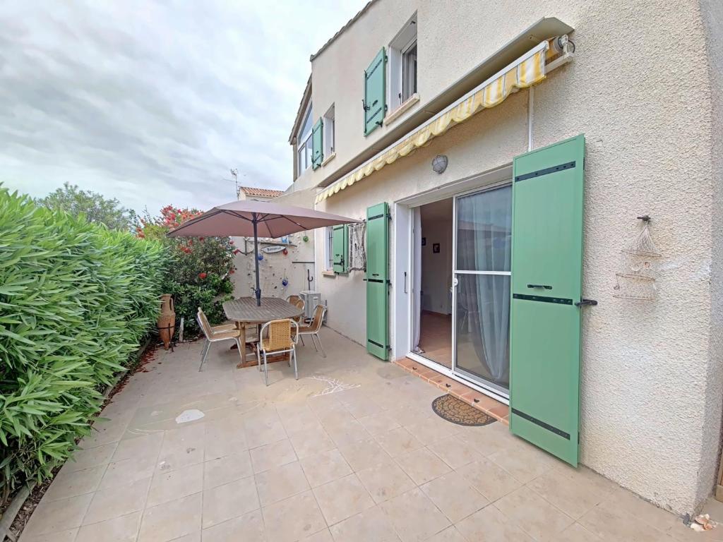 un patio avec une table et un parasol dans l'établissement Maison 4 pers aux Saintes-Maries-de-la-Mer - FR-1-475-158, à Saintes-Maries-de-la-Mer