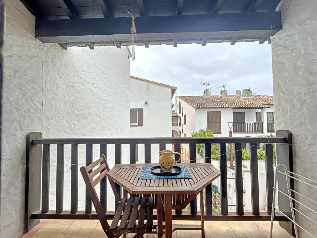 d'une table et d'une chaise en bois sur un balcon. dans l'établissement Studio 2-3 pers au cœur de Saintes-Maries-de-la-Mer - FR-1-475-160, à Saintes-Maries-de-la-Mer