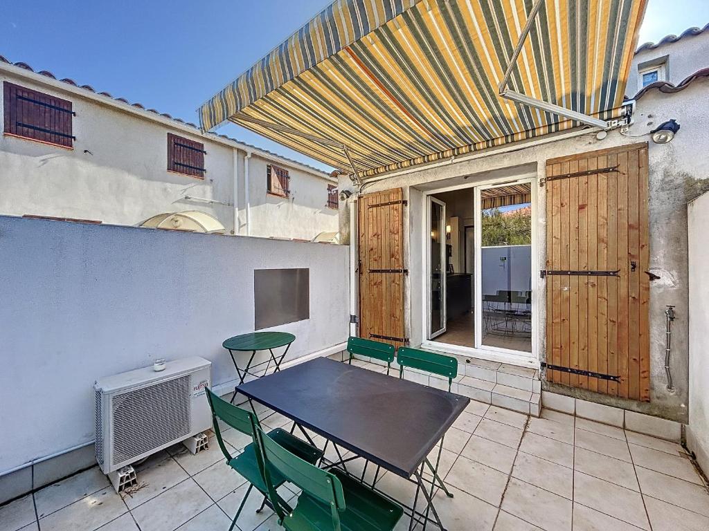 un patio avec une table et des chaises sur un balcon dans l'établissement Appartement 2 pièces proche centre, clim, terrasse - FR-1-475-169, à Saintes-Maries-de-la-Mer