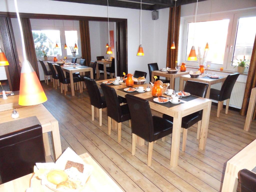 a restaurant with wooden tables and chairs and windows at Hotel Brandaris in Langeoog