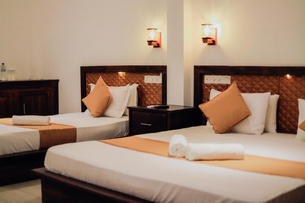 a hotel room with two beds with orange pillows at Sharta Yala in Tissamaharama