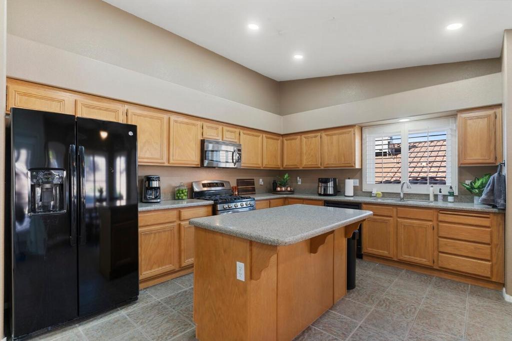 a kitchen with wooden cabinets and a black refrigerator at Bold Blue Retreat in Henderson in Las Vegas