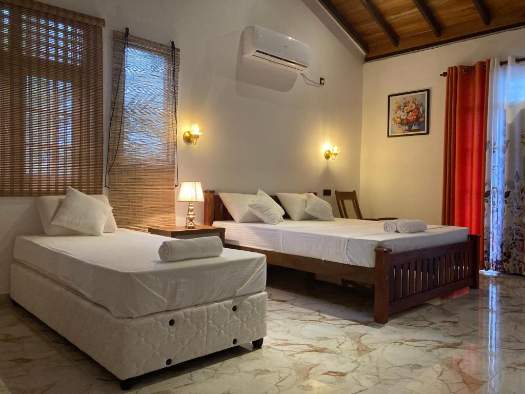 a bedroom with two beds and a table and a bedskirts at Margosa villa in Tangalle