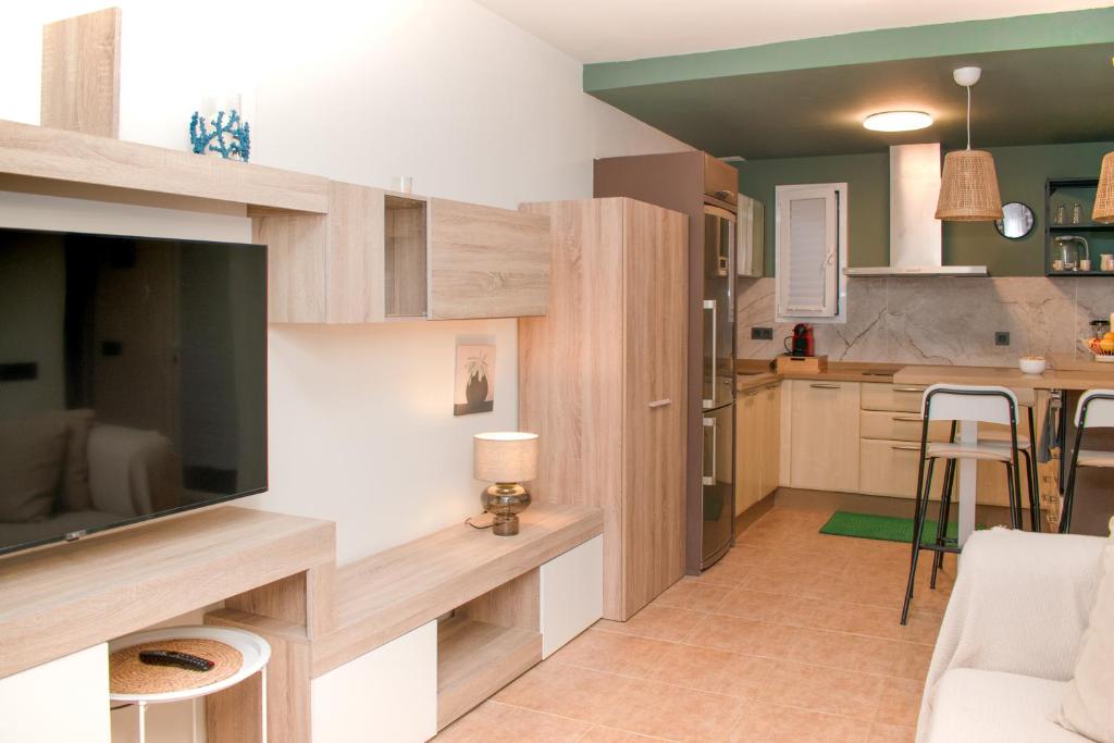 een woonkamer met een grote tv en een keuken bij The Blue Tajinaste in Caleta De Fuste